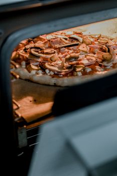 Close-up of a delicious homemade pizza with toppings baking in an oven.
