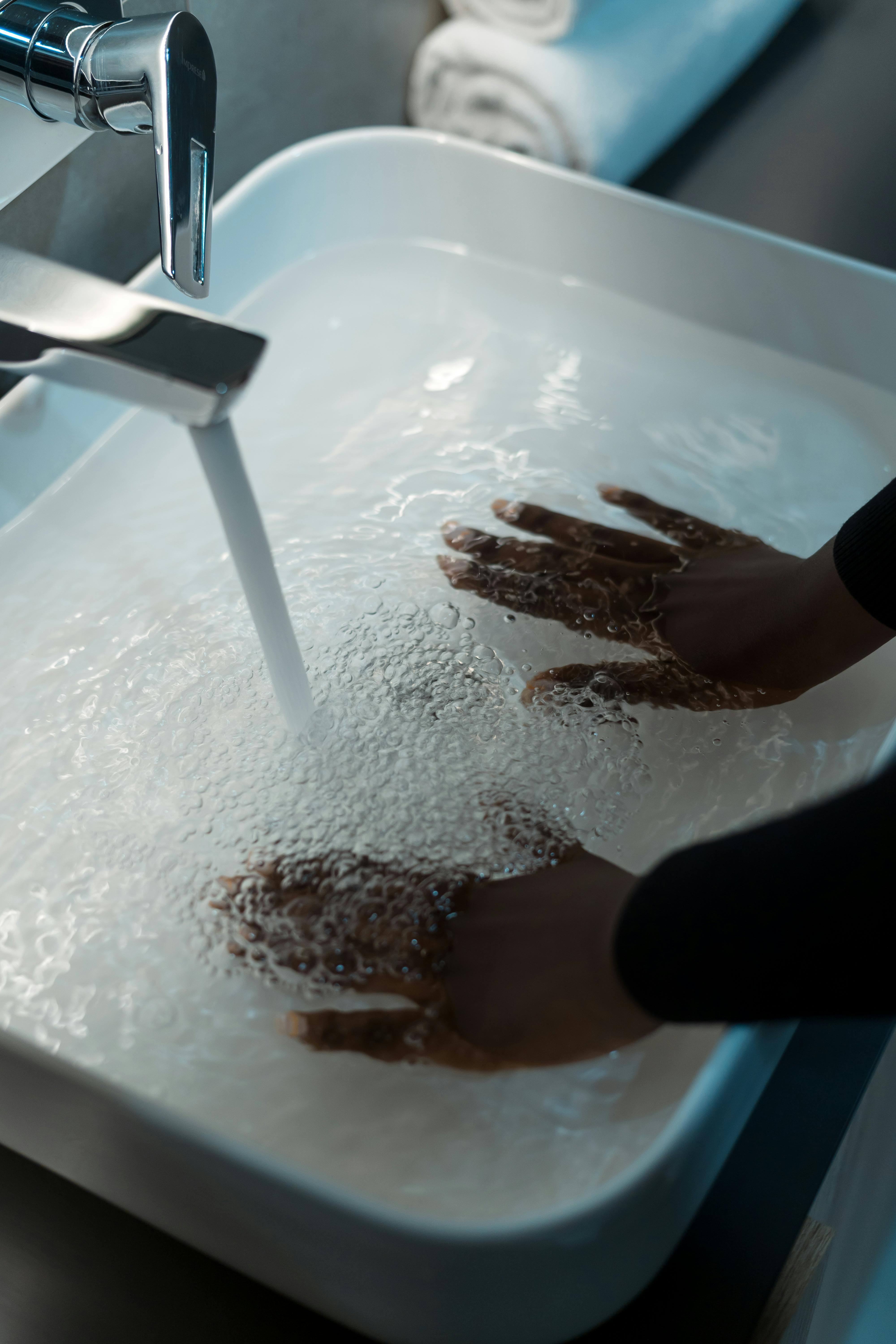 hands immersing in sink with water