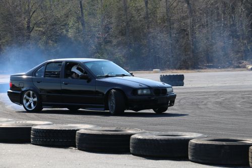 Free A black sedan expertly drifts on a track, surrounded by tire smoke, captured in dynamic motion. Stock Photo