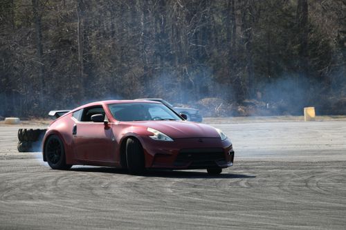 Free Red sports car performing an impressive drift on an asphalt track with smoke trails. Stock Photo