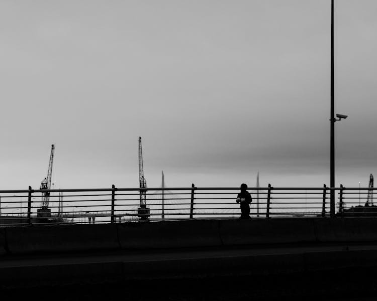 Silhouette Of Person Running On Bridge Near A Port