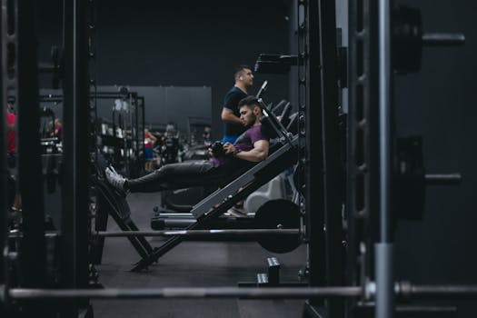 A man working out on a leg press machine surrounded by gym equipment.