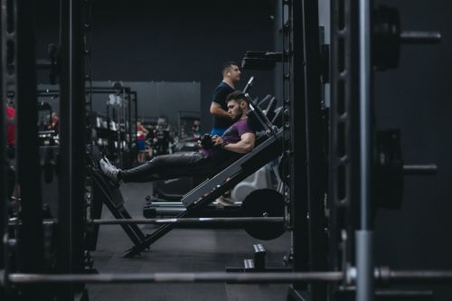 Free A man working out on a leg press machine surrounded by gym equipment. Stock Photo
