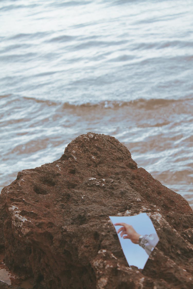 A Mirror On A Rock With A Reflection Of A Person's Hand