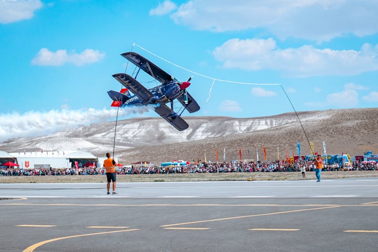 People Watching A Vintage Airplane During An Airshow 