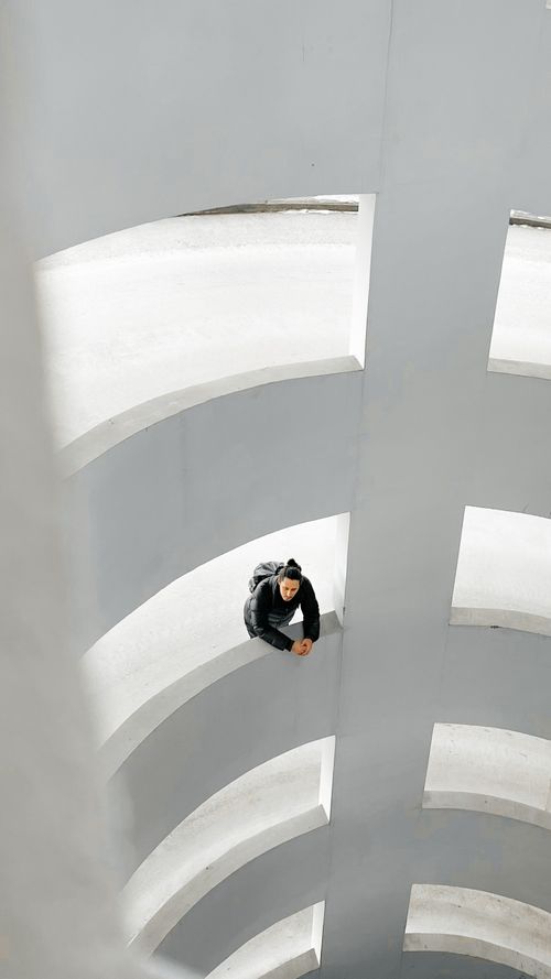 Free A person leaning on a railing in a spiral architecture emphasizes modern design. Stock Photo