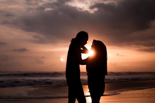 Free Silhouette of Man and Woman in the Beach During Sunset Stock Photo