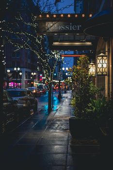 Nighttime city street scene with cars and festive string lights, capturing a cozy urban vibe.