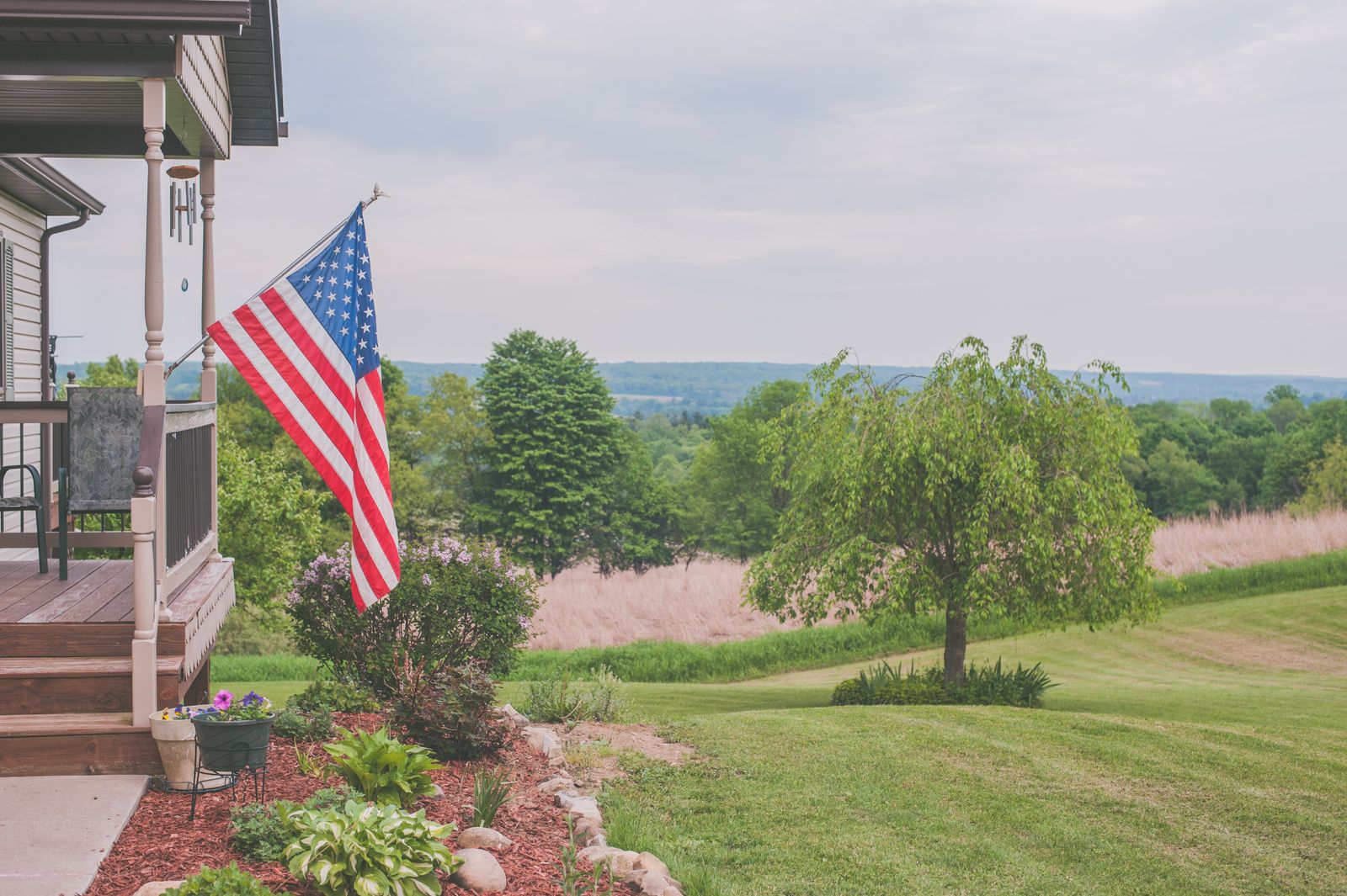 American flag displayed on a quiet porch with a green backyard view for Memorial Day