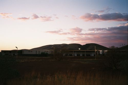 Free A serene view of an industrial area with hills and a colorful sunset sky. Stock Photo