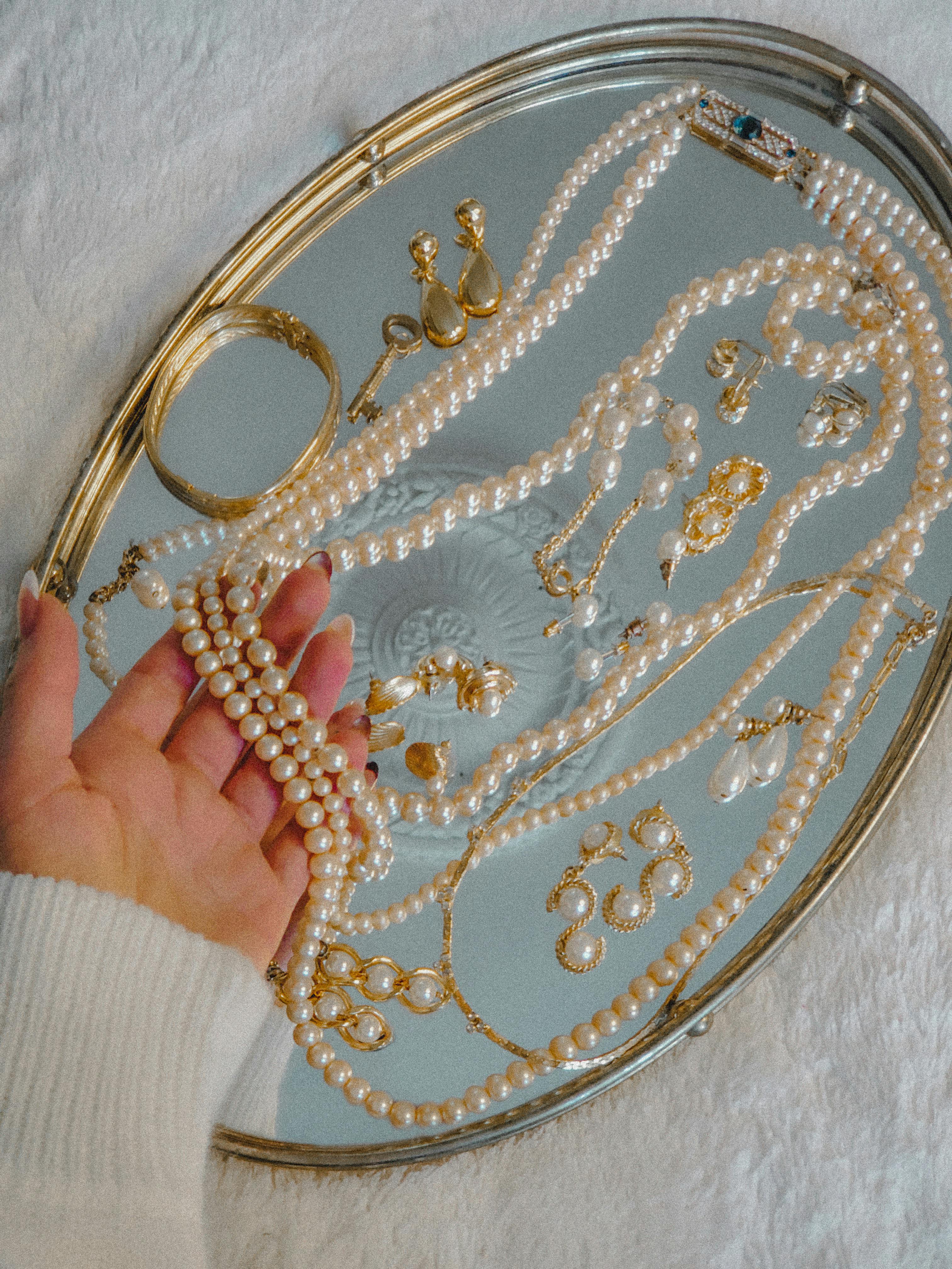 person holding a pearl necklace on silver tray