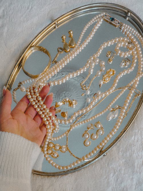 Person Holding a Pearl Necklace on Silver Tray