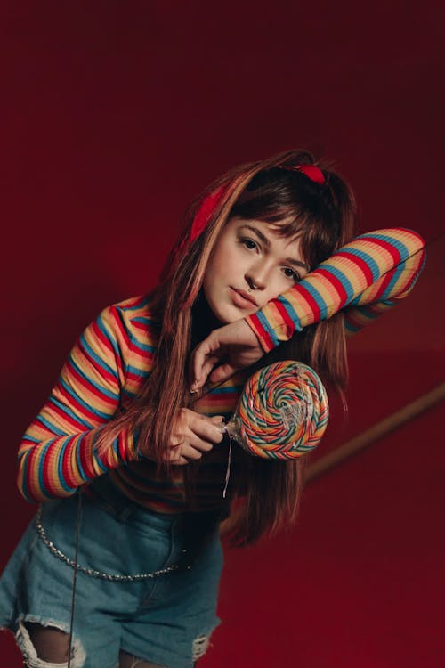 Photo of a Woman Leaning while Holding a Lollipop