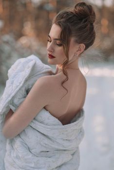 A woman with closed eyes wrapped in a soft blanket, standing elegantly in a winter wonderland.