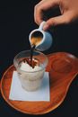 Male Hand Pouring Black Coffee into Glass of Whipped Cream