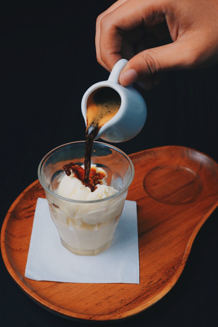 Male Hand Pouring Black Coffee Into Glass Of Whipped Cream