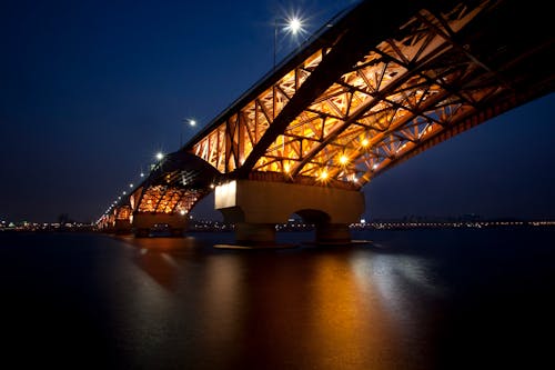 Illuminated Bridge over Body of Water during Night Time