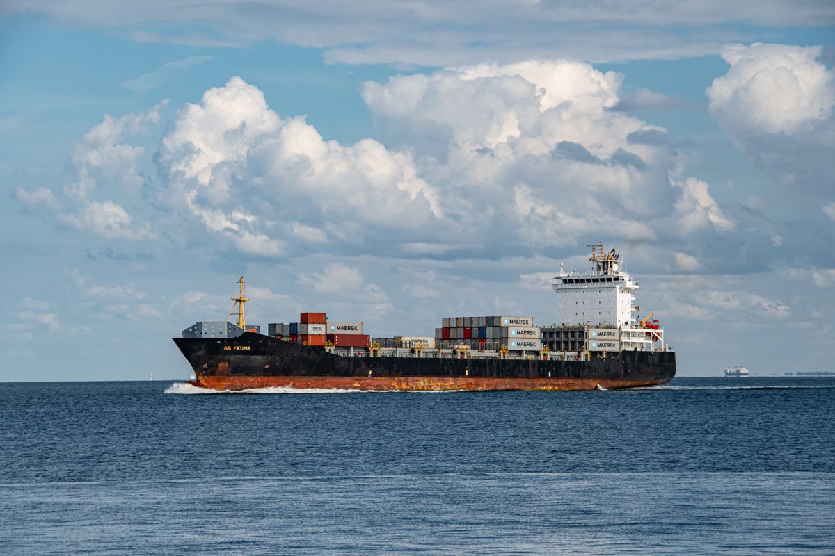 Cargo ship sailing under clear skies and white clouds