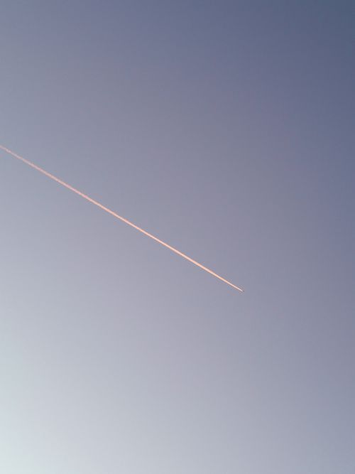 Free A streaking contrail from a jet aircraft is silhouetted against a clear blue sky. Stock Photo
