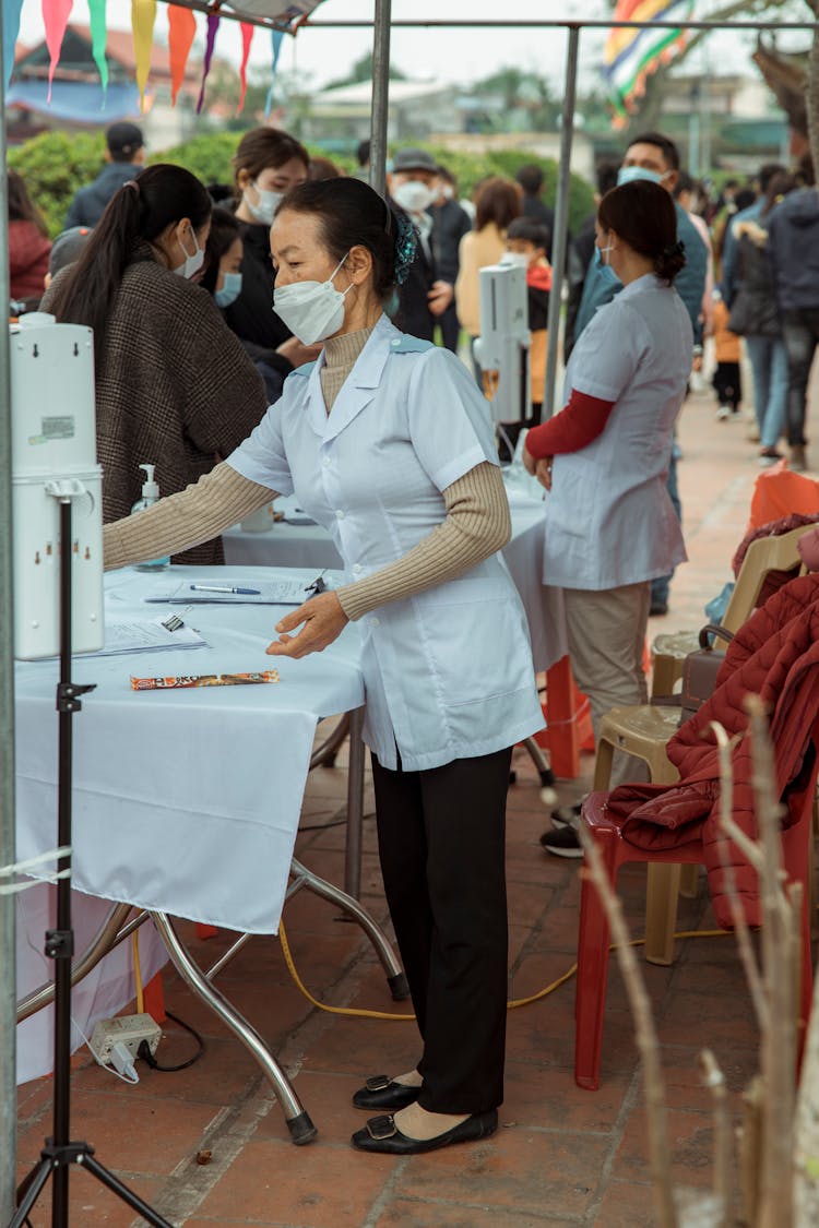 Woman In Mask And Shirt Working By Table