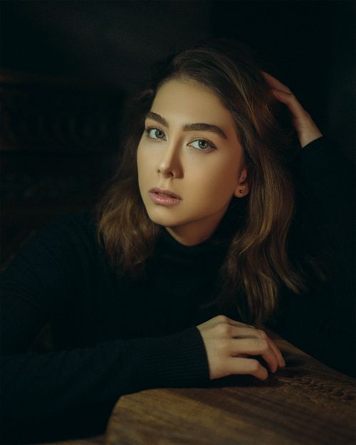 Free A beautiful portrait featuring a woman with long brown hair and serene expression, set against a moody background. Stock Photo