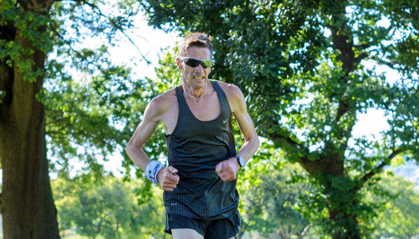 A person running along a tree-lined trail in daylight