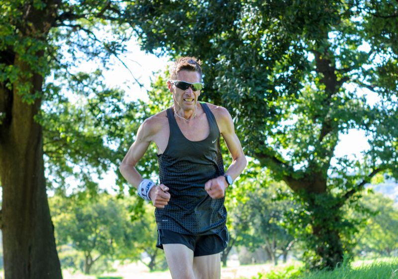 A person running along a tree-lined trail in daylight