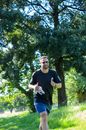 Man in Black Crew Neck T-shirt and Blue Denim Jeans Standing Near Green Trees during
