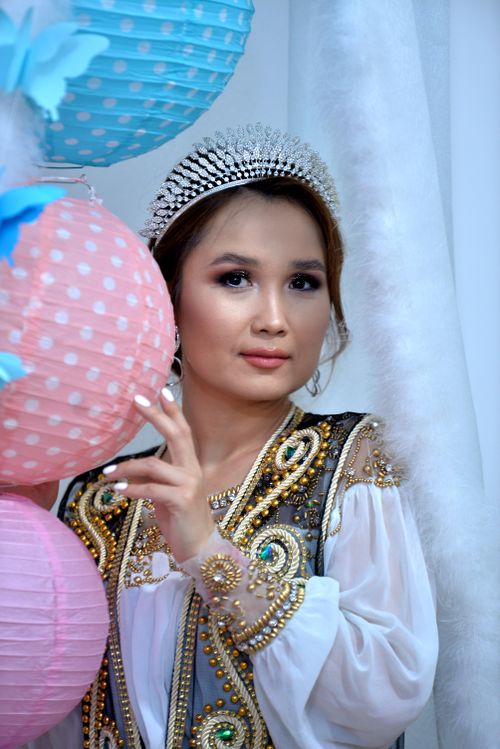 Free Woman wearing a jeweled dress and tiara, holding colorful lanterns in a festive setting. Stock Photo