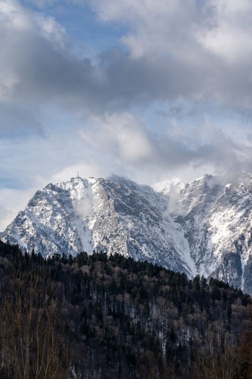 Free Scenic view of snow-covered mountains with a cloudy sky backdrop, offering a serene winter landscape. Stock Photo