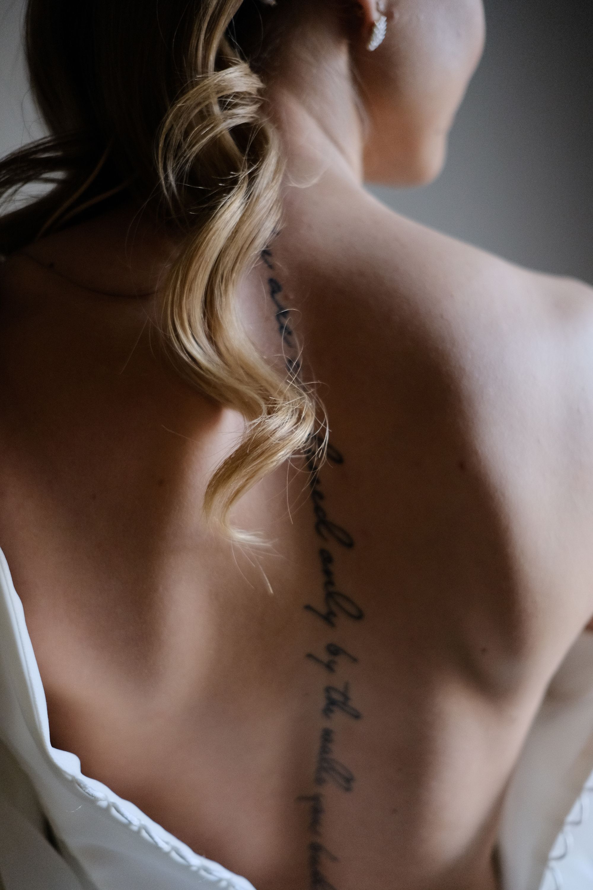 Client's back showing a healed fine-line script tattoo running down the spine