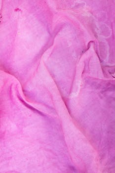 A close-up texture photo of pink fabric, showcasing its vibrant color and intricate folds.