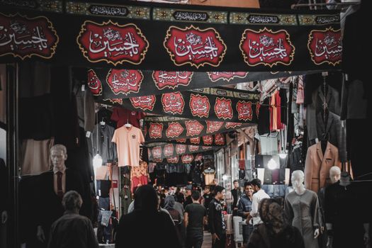 Explore the vibrant Iranian market at night with people shopping and colorful decorations.