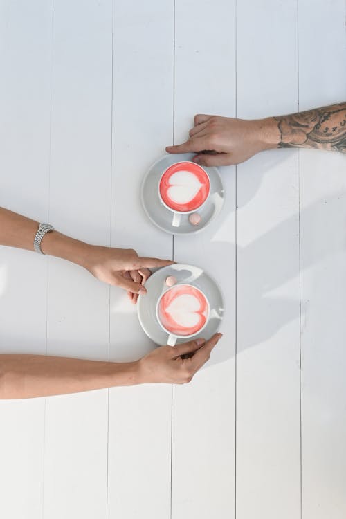 Free People Holding a Ceramic Saucers with Coffee Stock Photo