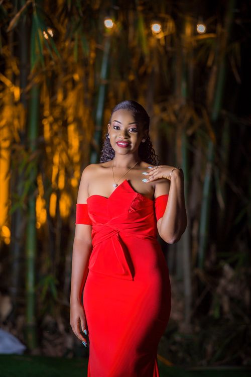 Free A graceful woman poses in a vibrant red dress against a bamboo backdrop in Auckland. Stock Photo