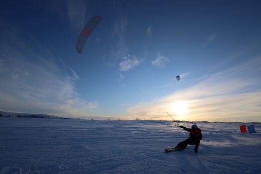 Exciting snowkiting in a winter landscape under a vibrant sunset sky.