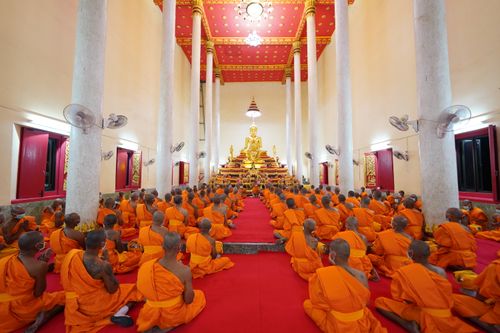 Free Monks in orange robes meditate inside a temple in Buriram, Thailand. Stock Photo