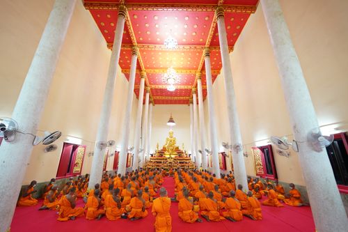 Free A group of Buddhist monks in traditional orange robes worship in a Buriram temple, Thailand. Stock Photo