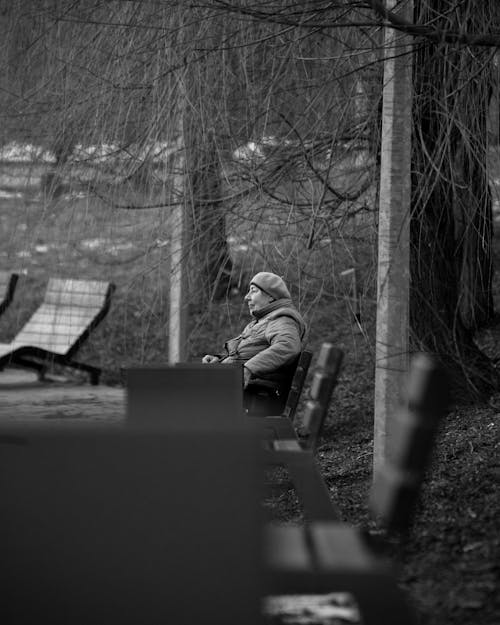Grayscale Photo of Man Sitting on Bench