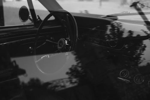 Grayscale Photo of a Vintage Car Steering Wheel