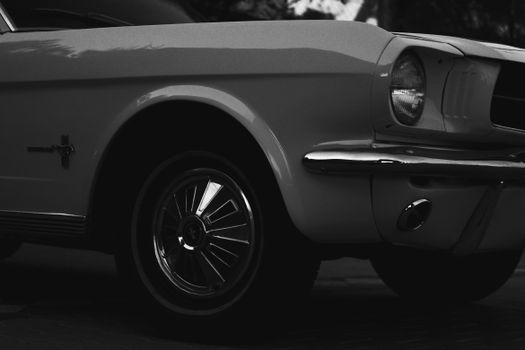 Close-up of a classic Ford Mustang in monochrome, showcasing the headlight and wheel.