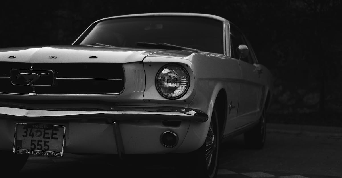 Close-up of a vintage Ford Mustang in grayscale, showcasing classic automotive design.