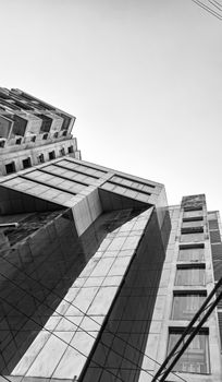 A striking architectural composition captures modern high-rise buildings in black and white from a low angle.