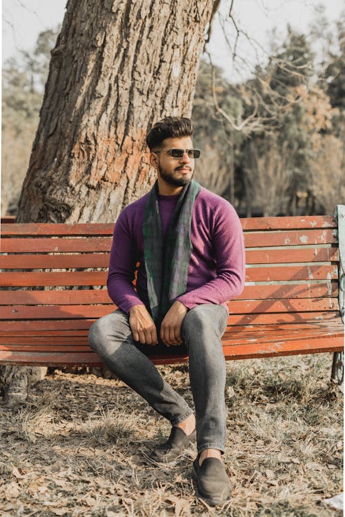 Free A Man in Purple Sweater Sitting on Brown Wooden Bench Stock Photo