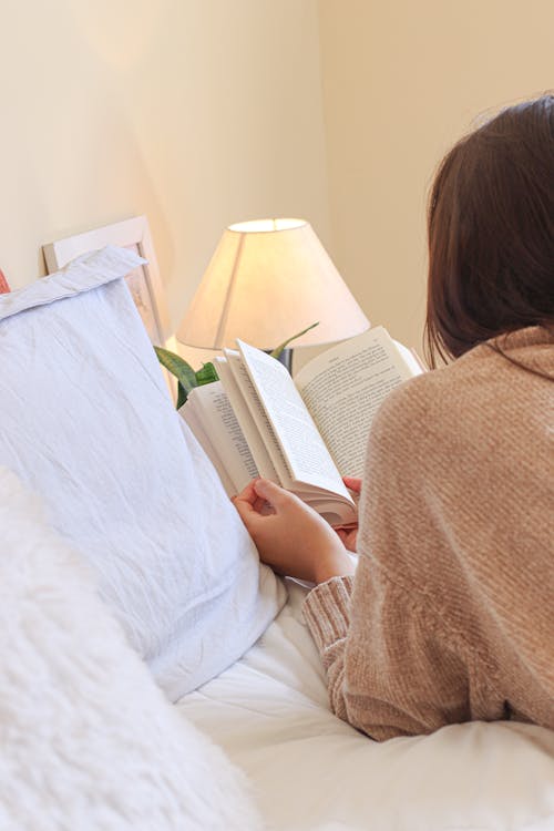 Free 

A Woman Reading a Book on a Bed Stock Photo
