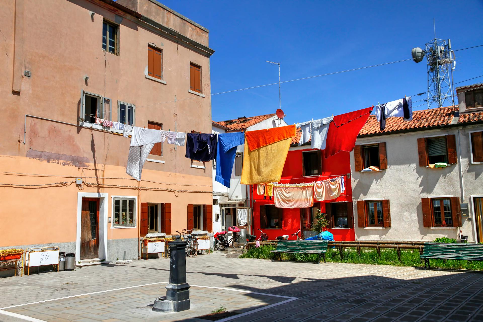 Brightly colored clothes drying outside old European buildings under clear blue sky.