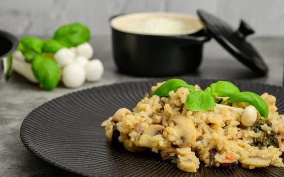 Close-up of creamy mushroom risotto topped with basil on a black plate, perfect for foodies.