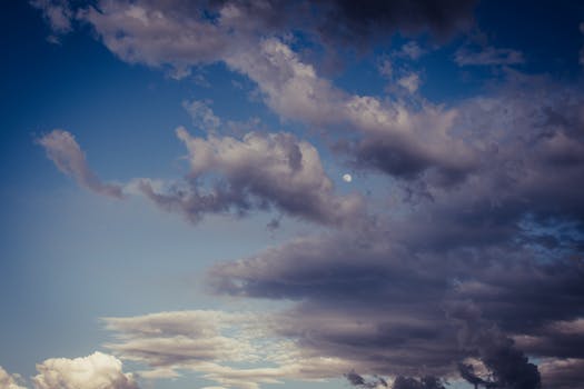 Beautiful cloudy sky with the moon visible, creating a dramatic atmosphere at dusk.