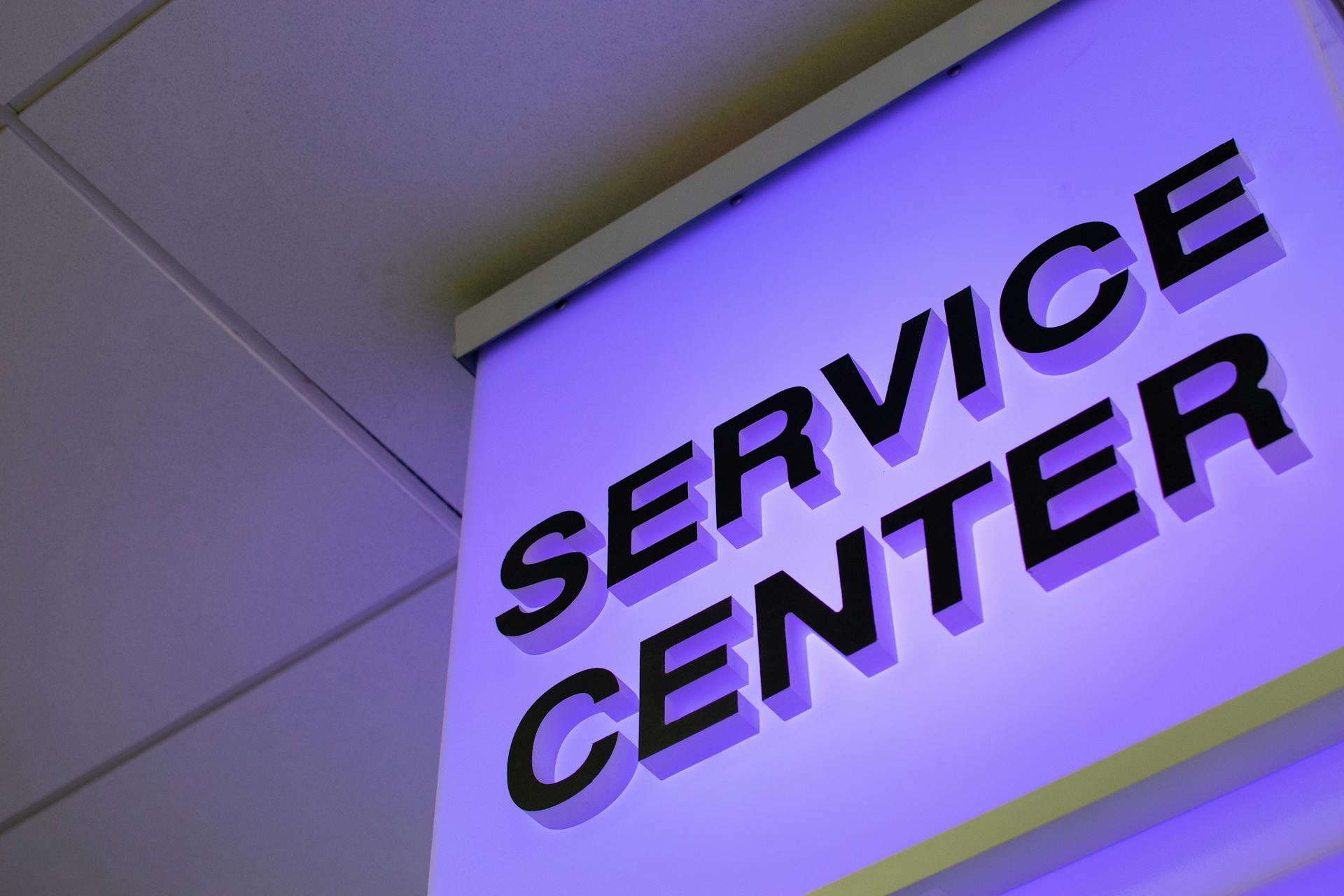 Close-up of a modern illuminated Service Center sign in a building interior.