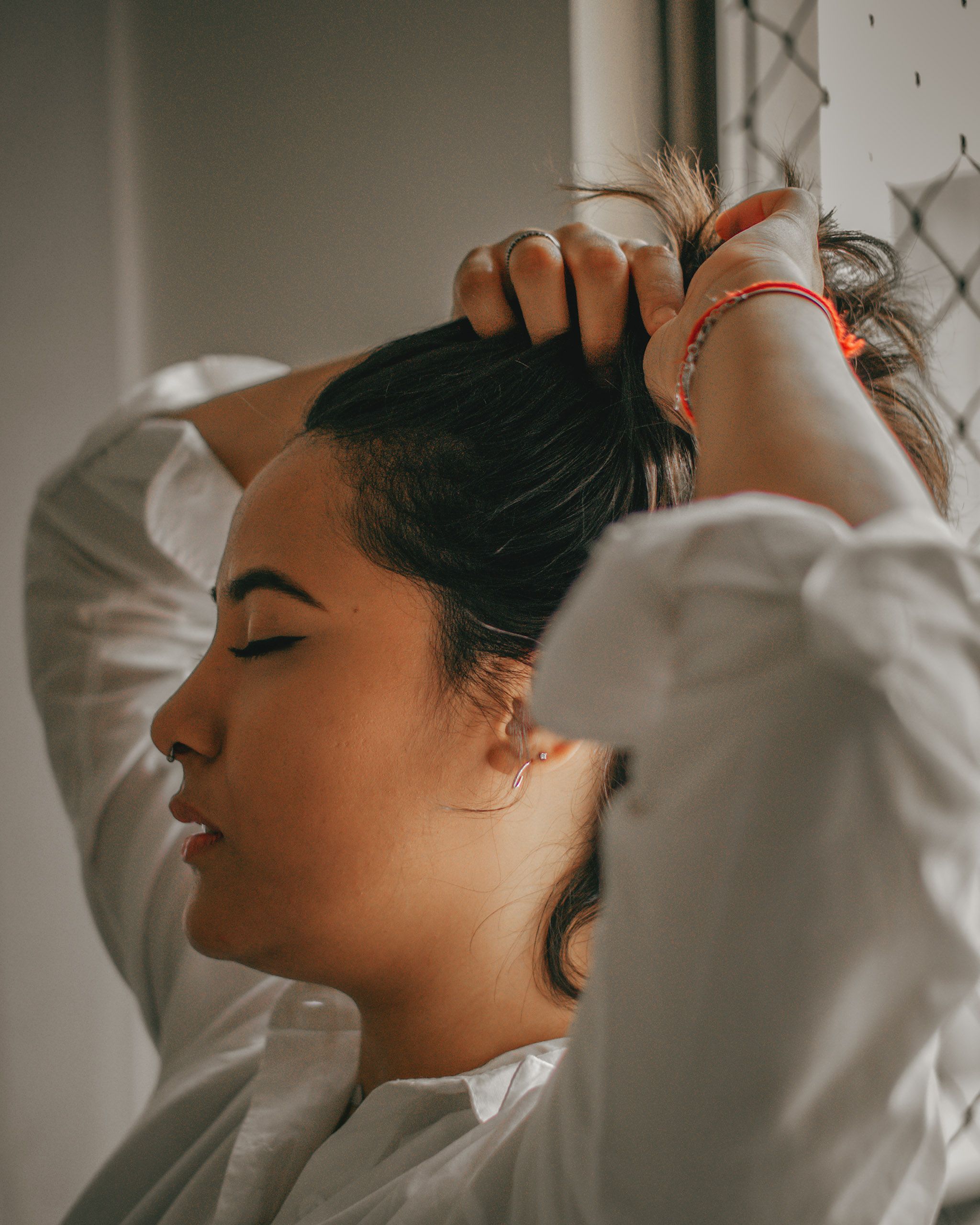 Woman with eyes closed holding her hair, conveying a peaceful and introspective mood.